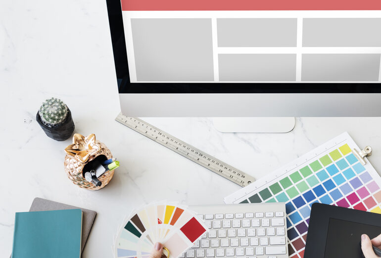 Designer working with computer and colour palettes on a creative project