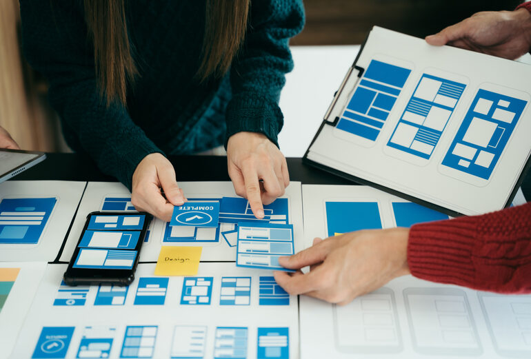 Design team planning UI/UX layouts with app mockups